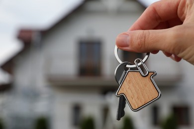 Photo of Woman holding house keys outdoors, closeup with space for text. Real estate agent