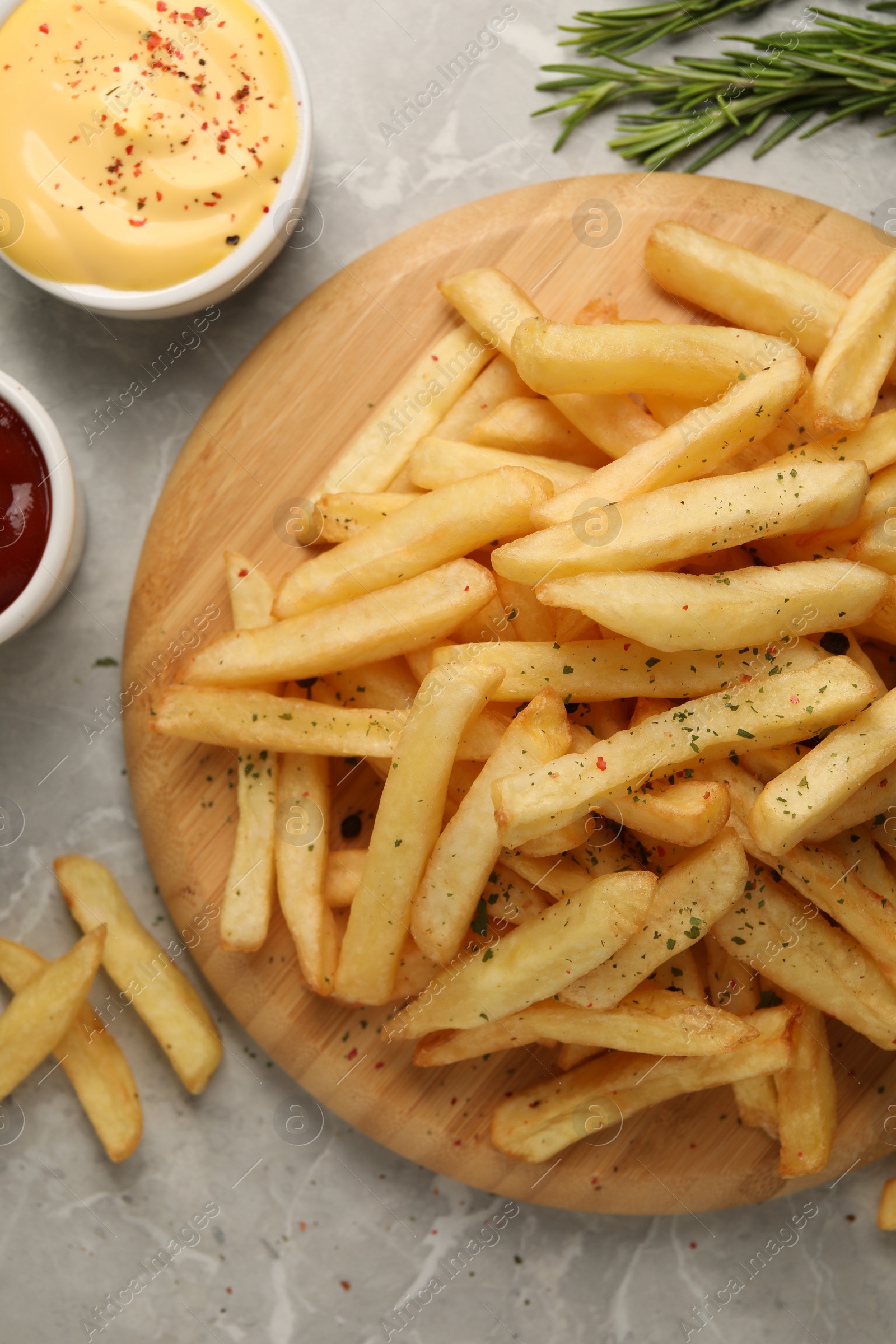 Photo of Delicious french fries served with sauces on grey marble table, flat lay