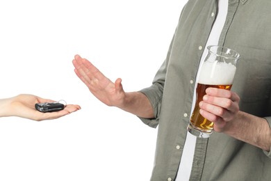Photo of Man with glass of beer refusing drive car while woman suggesting him keys on white background, closeup. Don't drink and drive concept