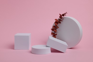 Photo of Scene for product presentation. Podiums of different geometric shapes and dry eucalyptus on light pink background