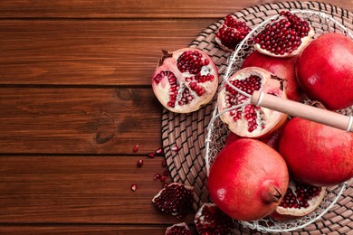 Photo of Delicious ripe pomegranates on wooden table, flat lay. Space for text