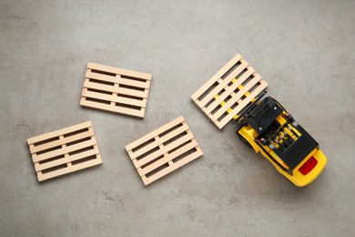 Photo of Toy forklift and wooden pallets on light grey table, flat lay