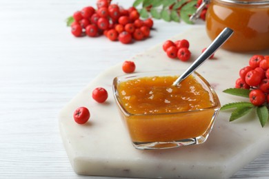 Delicious rowan jam in glass bowl on white wooden table. Space for text