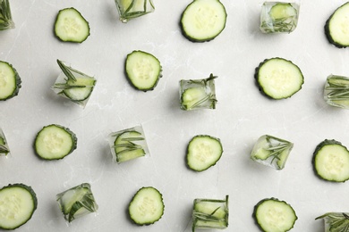Photo of Flat lay composition with ice cubes and fresh cucumber slices on grey background