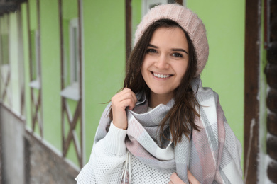 Photo of Young woman wearing warm sweater and scarf  outdoors on snowy day. Winter season