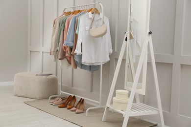 Rack with stylish women's clothes and mirror in dressing room