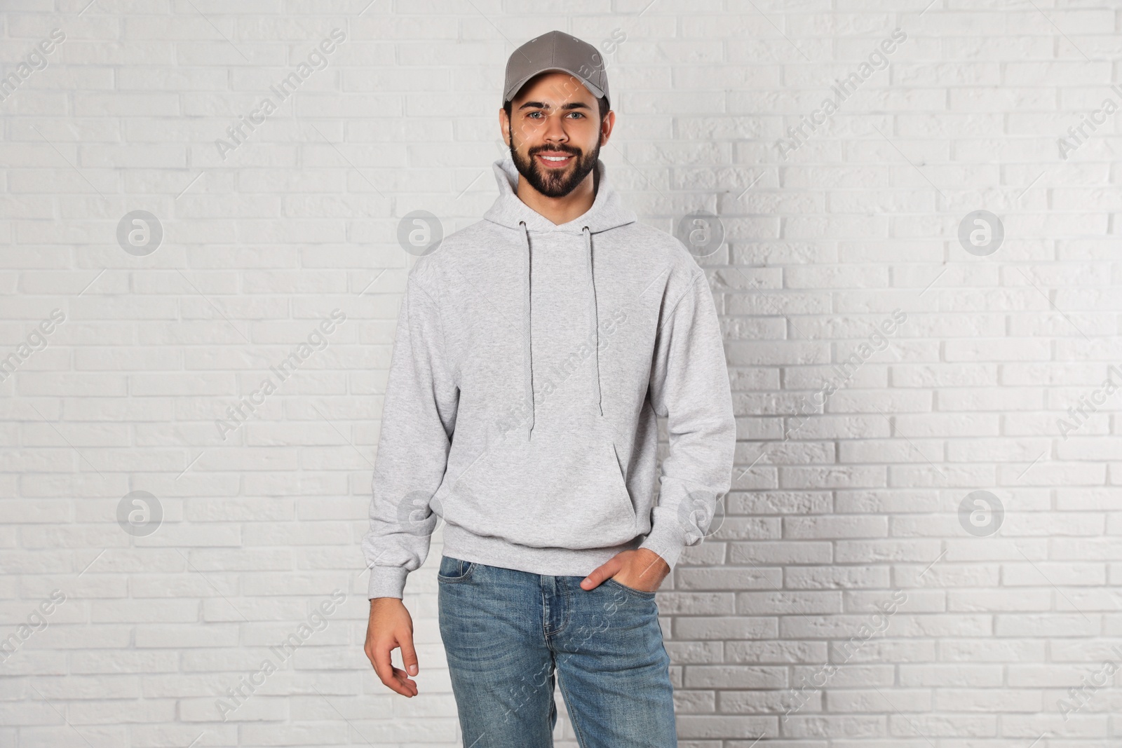 Photo of Portrait of young man in sweater at brick wall. Mock up for design
