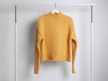 Photo of Warm sweater hanging on rack against white background