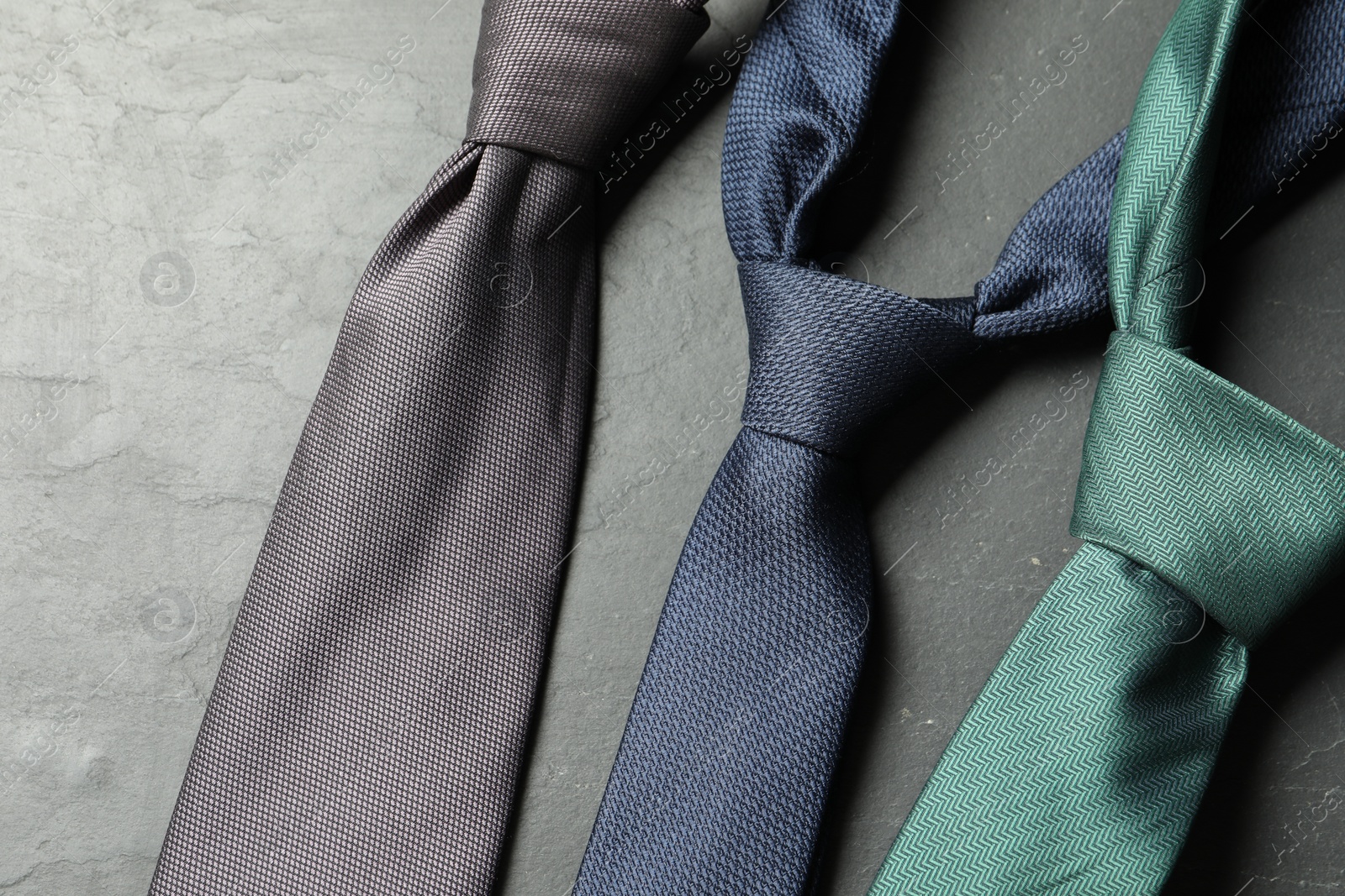 Photo of Different neckties on grey textured table, flat lay