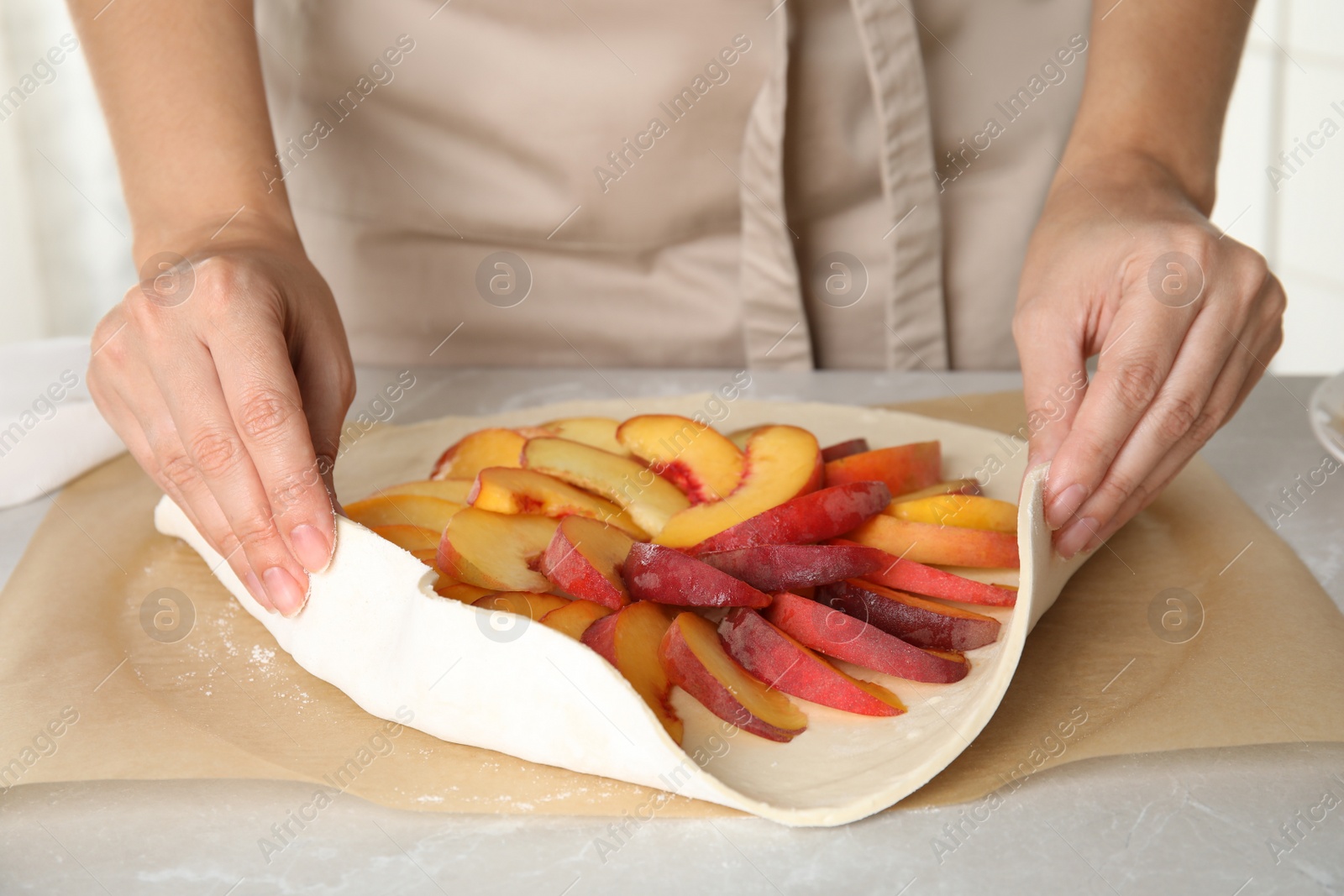 Photo of Woman making peach pie at kitchen table, closeup