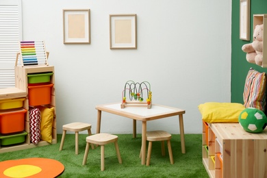 Photo of Stylish playroom interior with table and stools