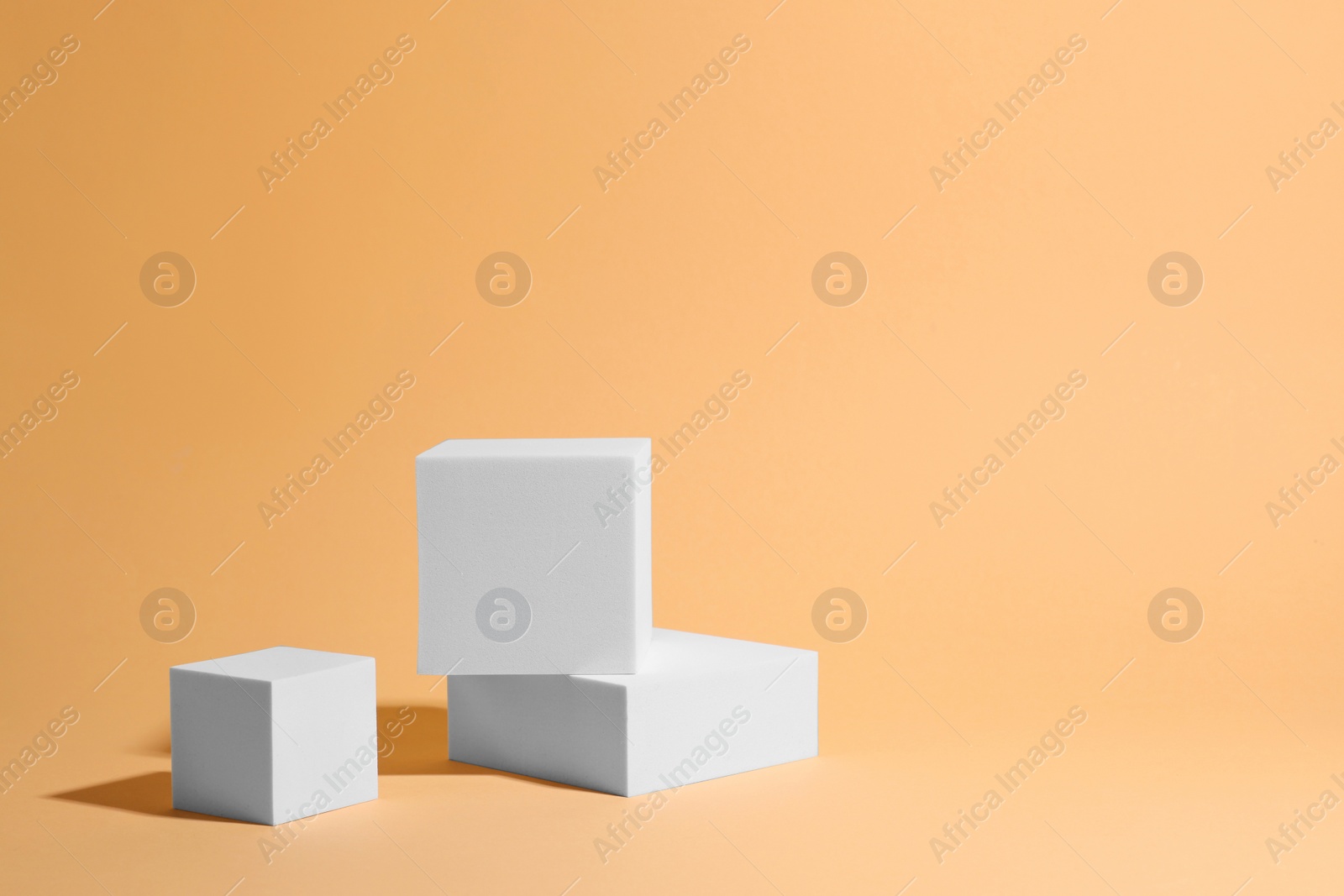 Photo of Scene for product presentation. Podiums of different geometric shapes on pale orange background, space for text