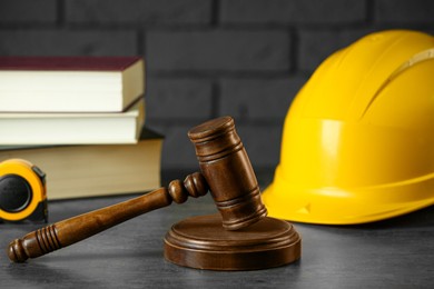 Construction and land law concepts. Judge gavel, protective helmet, tape measure with books on grey table