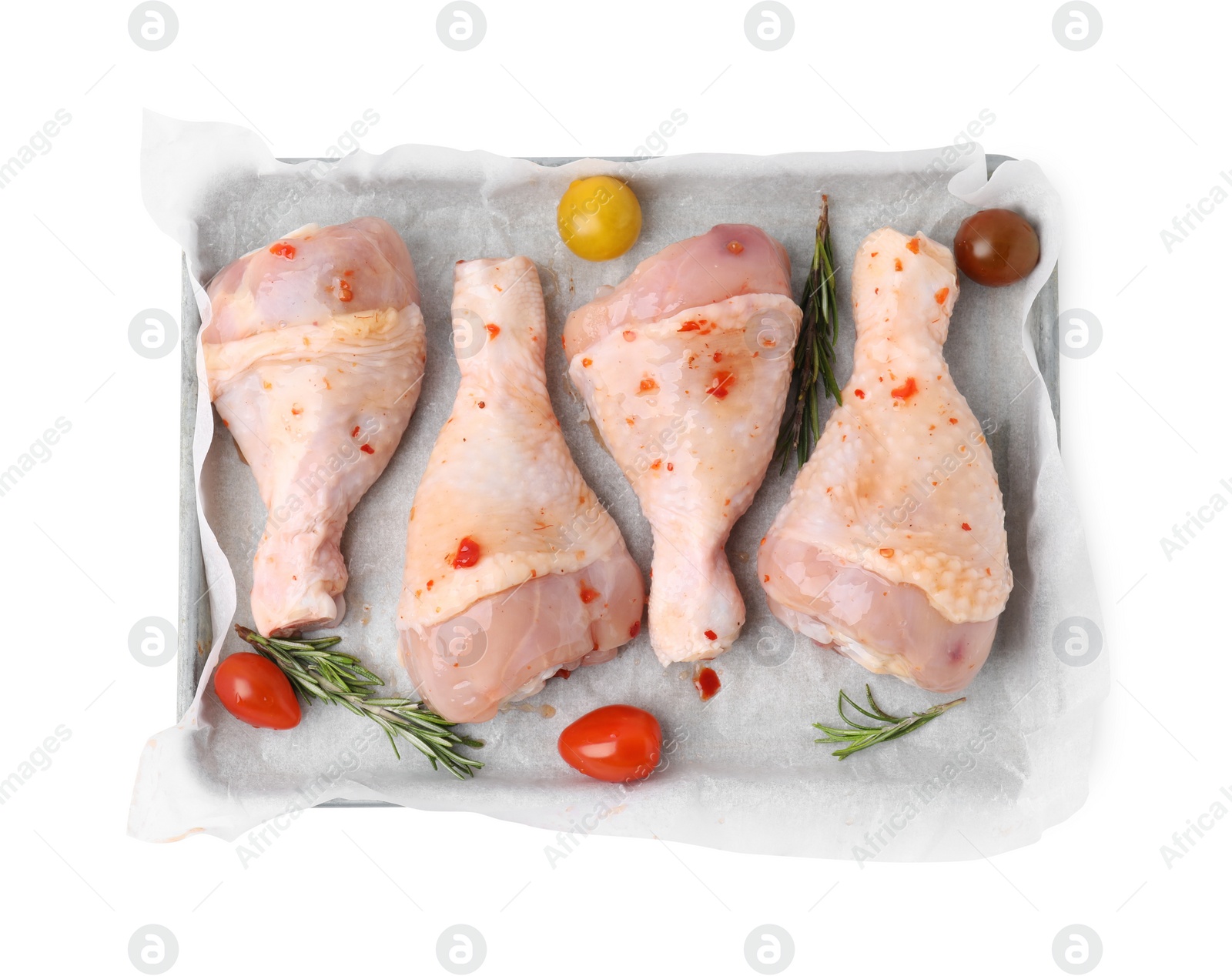 Photo of Raw marinated chicken drumsticks, rosemary and tomatoes in baking dish isolated on white, top view