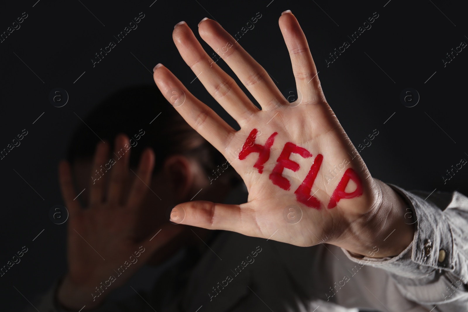 Photo of Woman with word Help written on hand against black background, closeup. Domestic violence concept