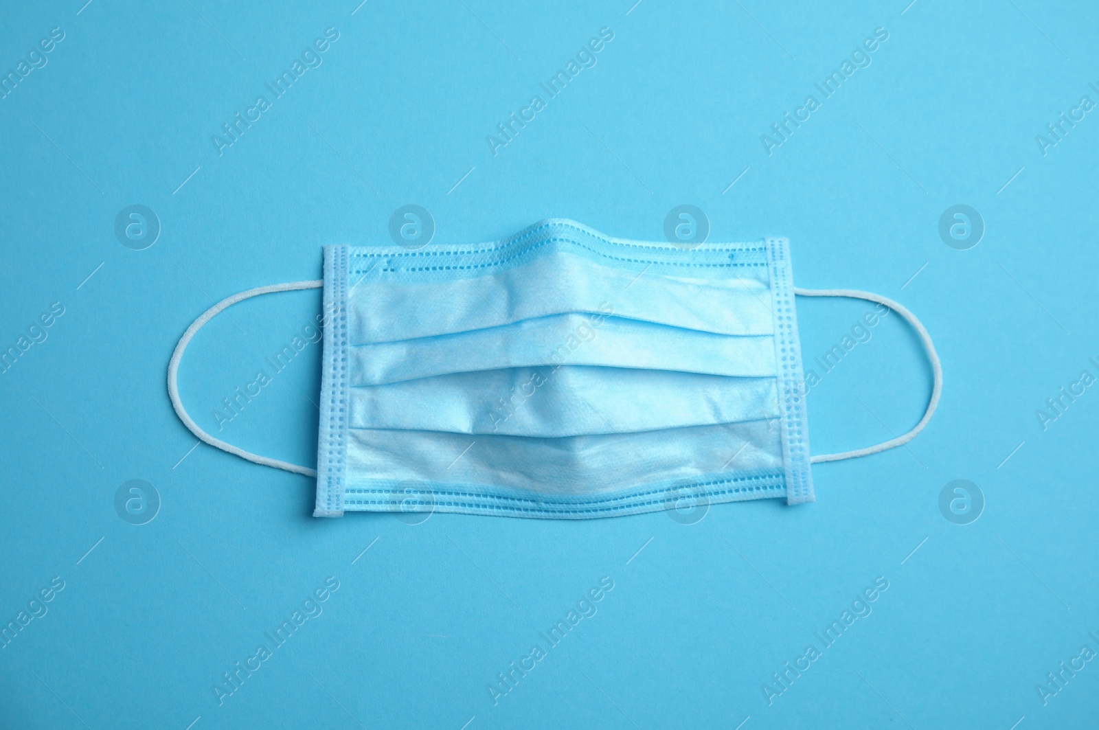 Photo of Medical face mask on blue background, top view