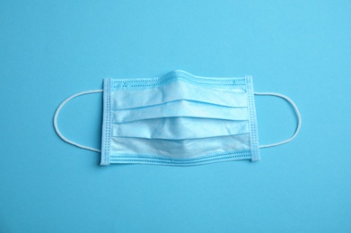 Photo of Medical face mask on blue background, top view