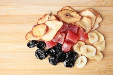 Photo of Pile of different tasty dried fruits on wooden table, flat lay