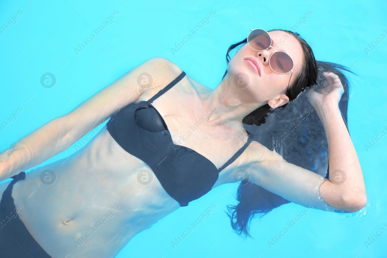 Photo of Young woman wearing stylish black bikini in swimming pool