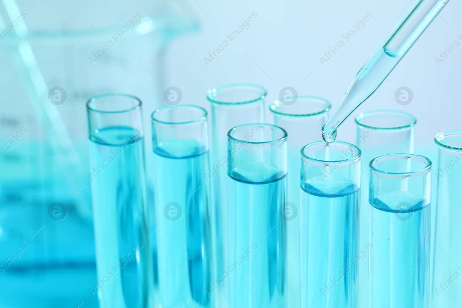 Photo of Dripping liquid from pipette into test tube on blurred background, closeup. Laboratory analysis