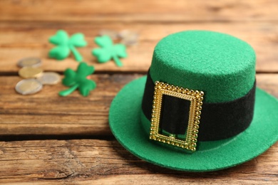 Photo of Leprechaun hat, decorative clover leaves and coins on wooden background, space for text. St Patrick's Day celebration