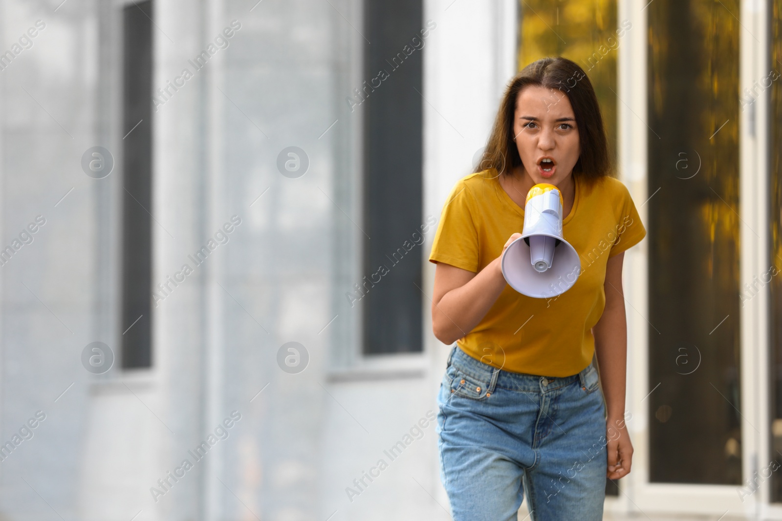 Image of Emotional young woman with megaphone outdoors. Protest leader