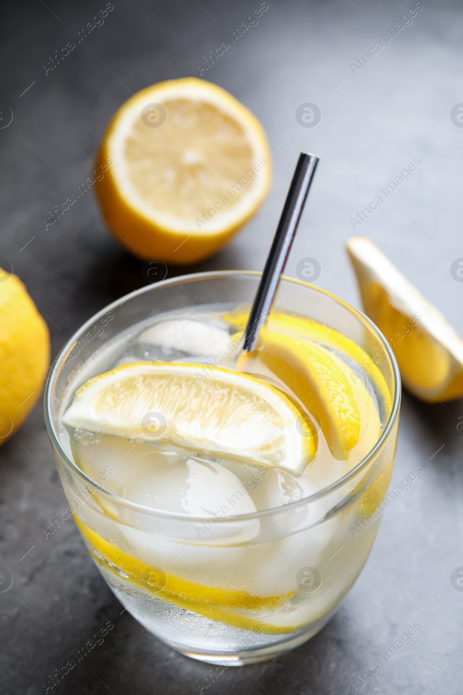 Photo of Soda water with lemon slices and ice cubes on grey table