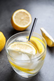 Soda water with lemon slices and ice cubes on grey table