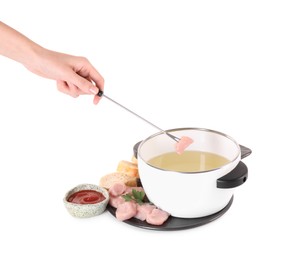Woman dipping piece of raw meat into oil in fondue pot on white background