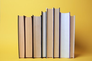 Photo of Collection of hardcover books on yellow background