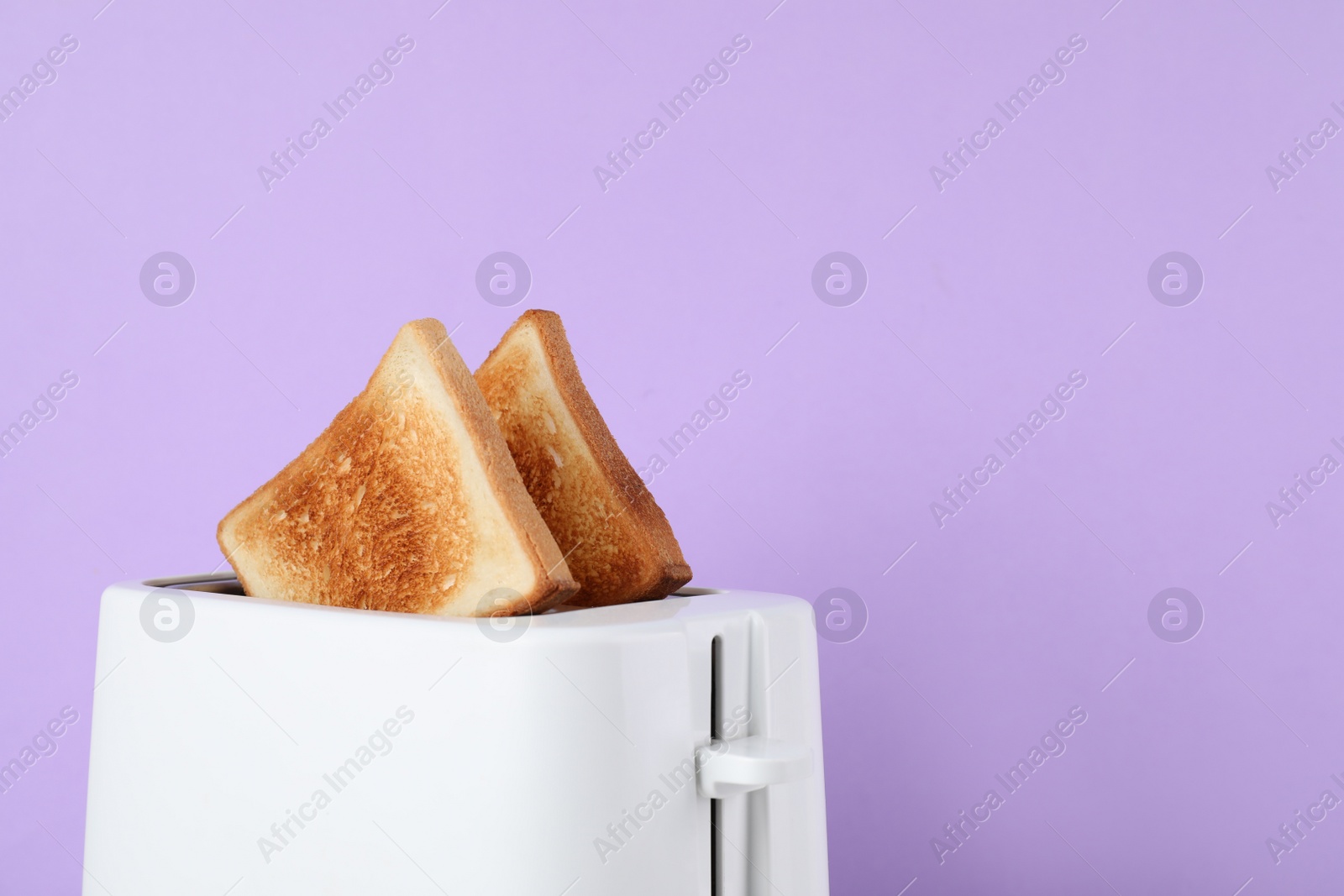 Photo of Modern toaster with slices of bread on lilac background, closeup. Space for text