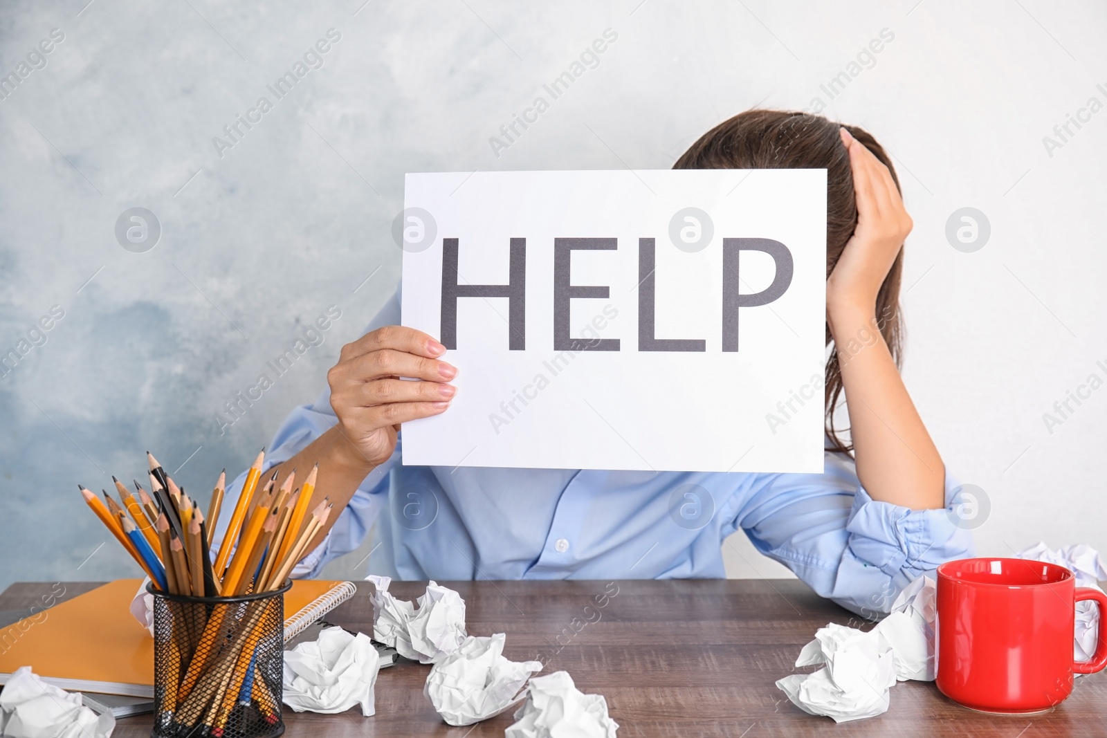 Photo of Woman holding card with word "HELP" at table in office