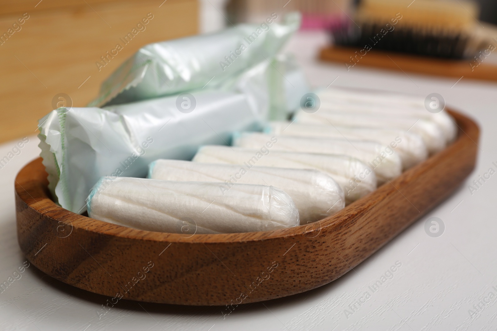 Photo of Wooden tray with many tampons on white table, closeup. Menstrual hygienic product