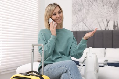 Photo of Smiling guest talking on smartphone in stylish hotel room