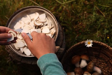 Photo of Man slicing freshly picked mushrooms outdoors, closeup