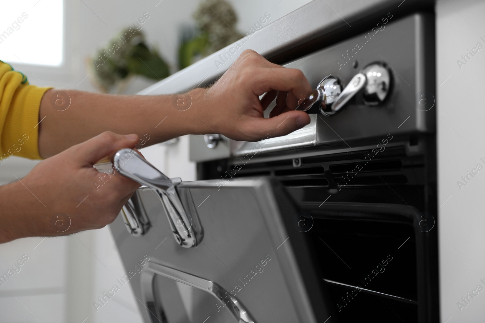 Photo of Man using modern oven in kitchen, closeup