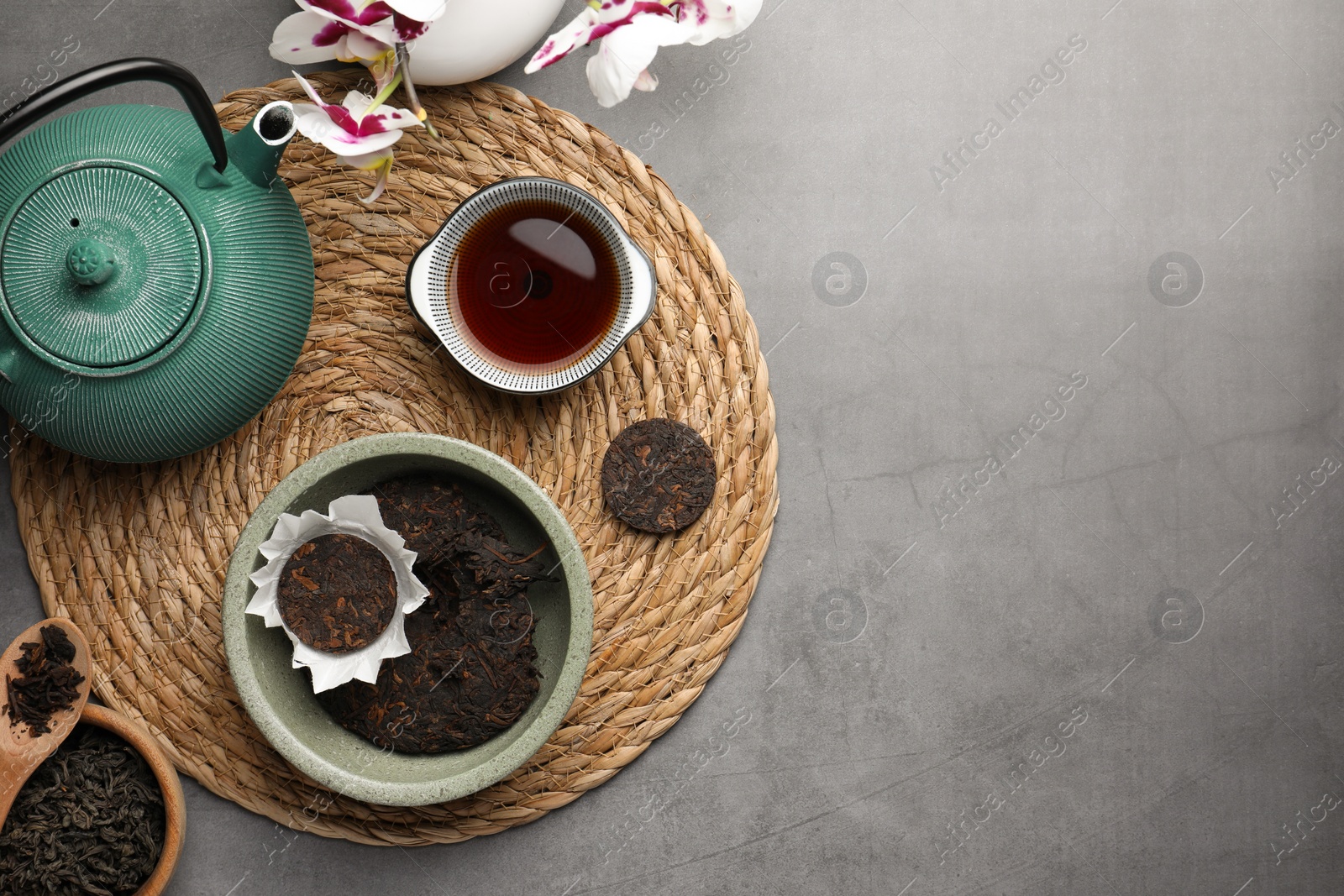 Photo of Flat lay composition with aromatic pu-erh tea on grey table. Space for text