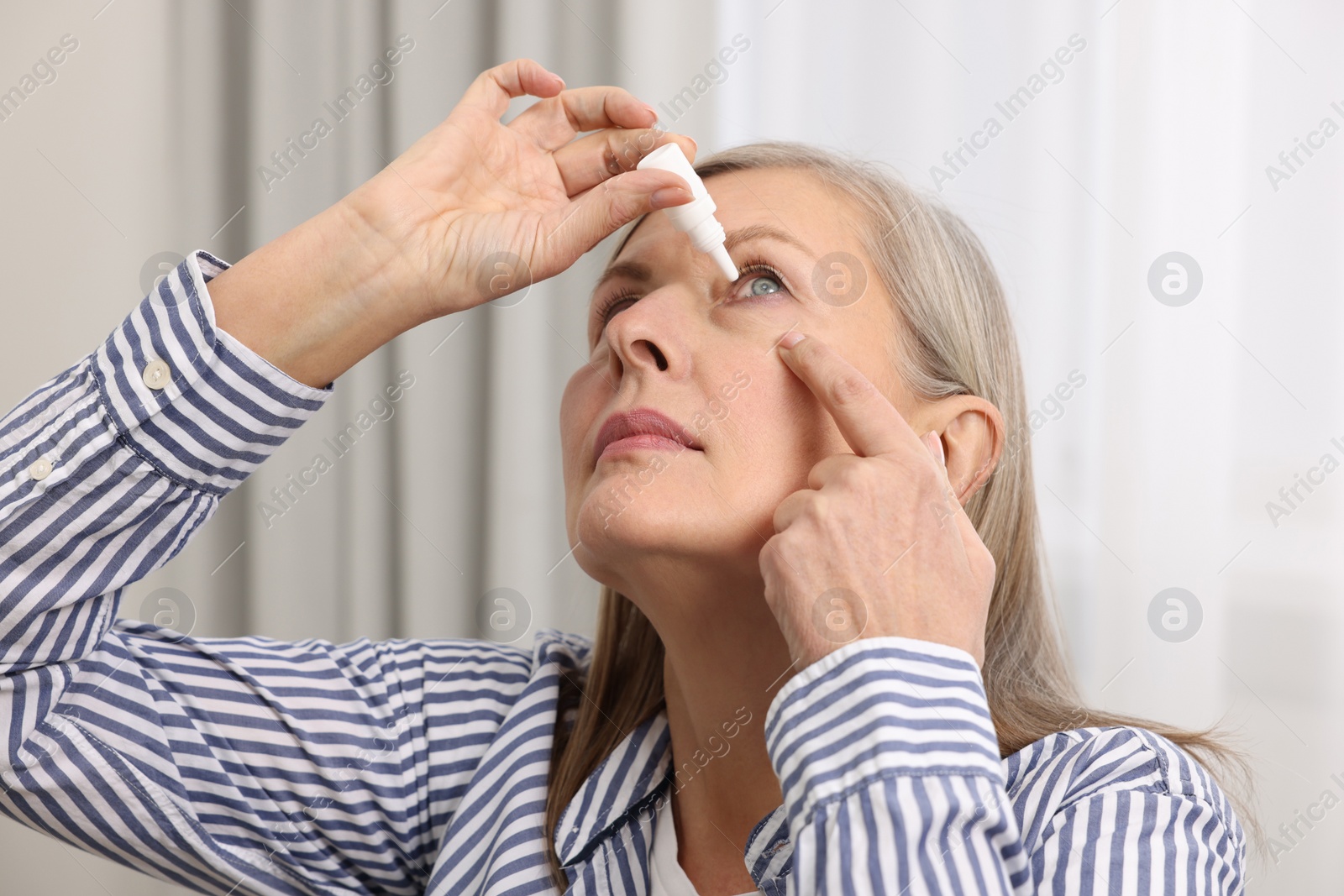 Photo of Woman applying medical eye drops at home