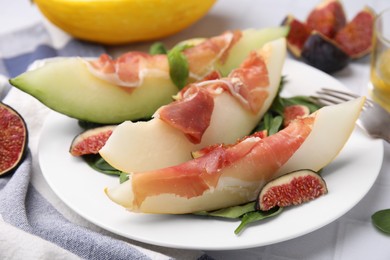 Photo of Tasty melon, jamon and figs served on plate, closeup