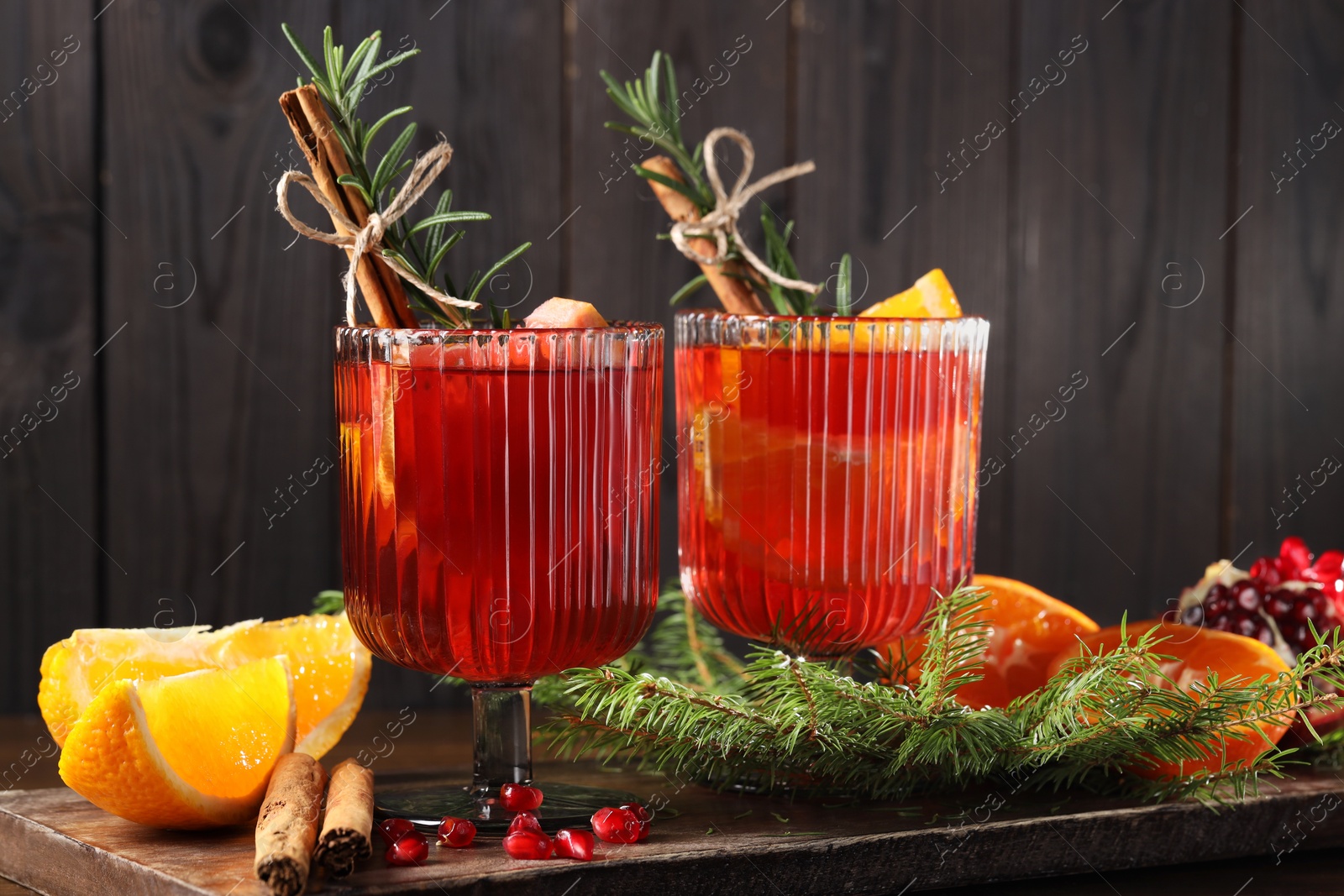 Photo of Christmas Sangria cocktail in glasses, ingredients and fir tree branches on table