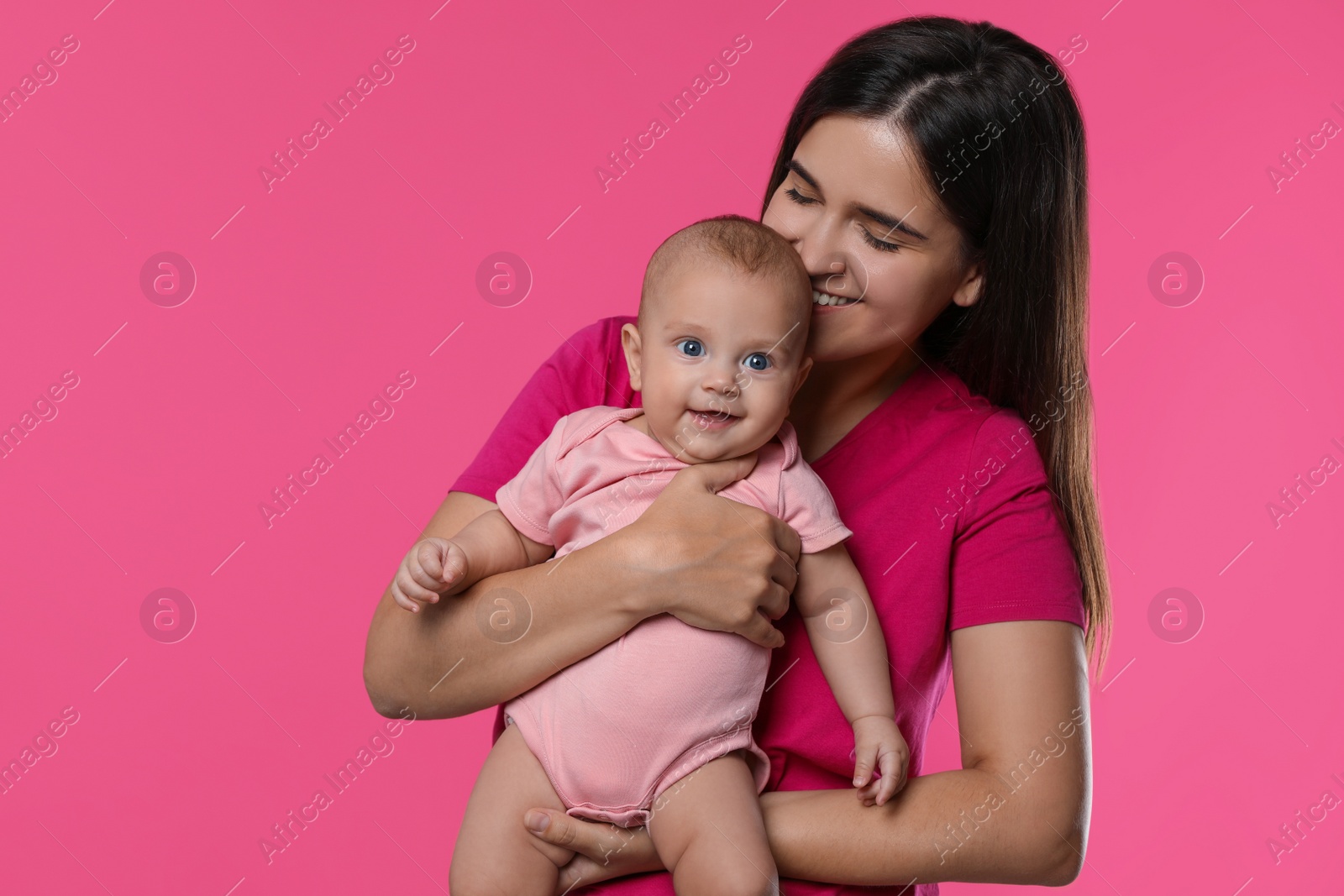 Photo of Beautiful mother with her cute baby on pink background. Space for text