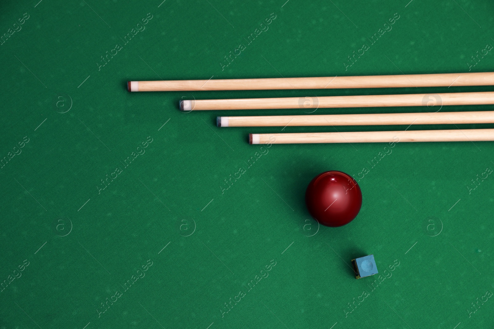 Photo of Red billiard ball, chalk and cues on table, flat lay. Space for text