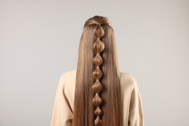 Woman with braided hair on grey background, back view