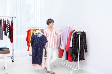 Beautiful young stylist choosing clothes in studio