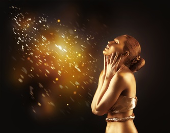 Photo of Portrait of beautiful lady with gold paint on skin against blurred lights. Space for text