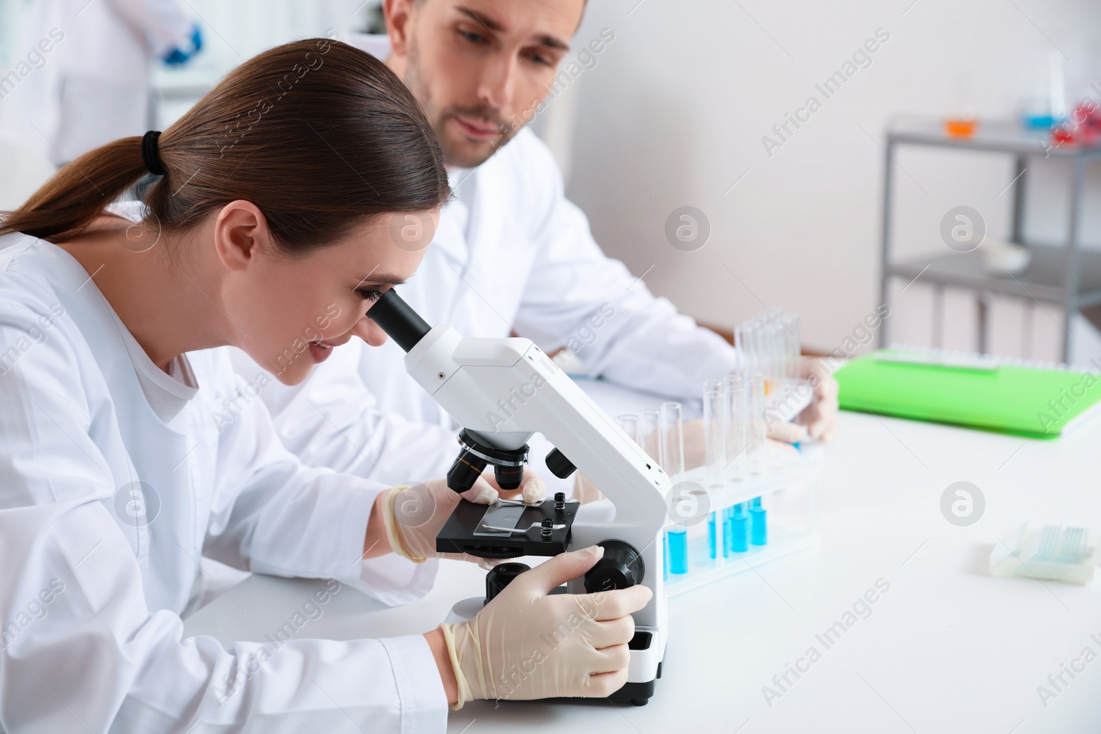 Photo of Scientist with microscope and colleague in laboratory. Medical research