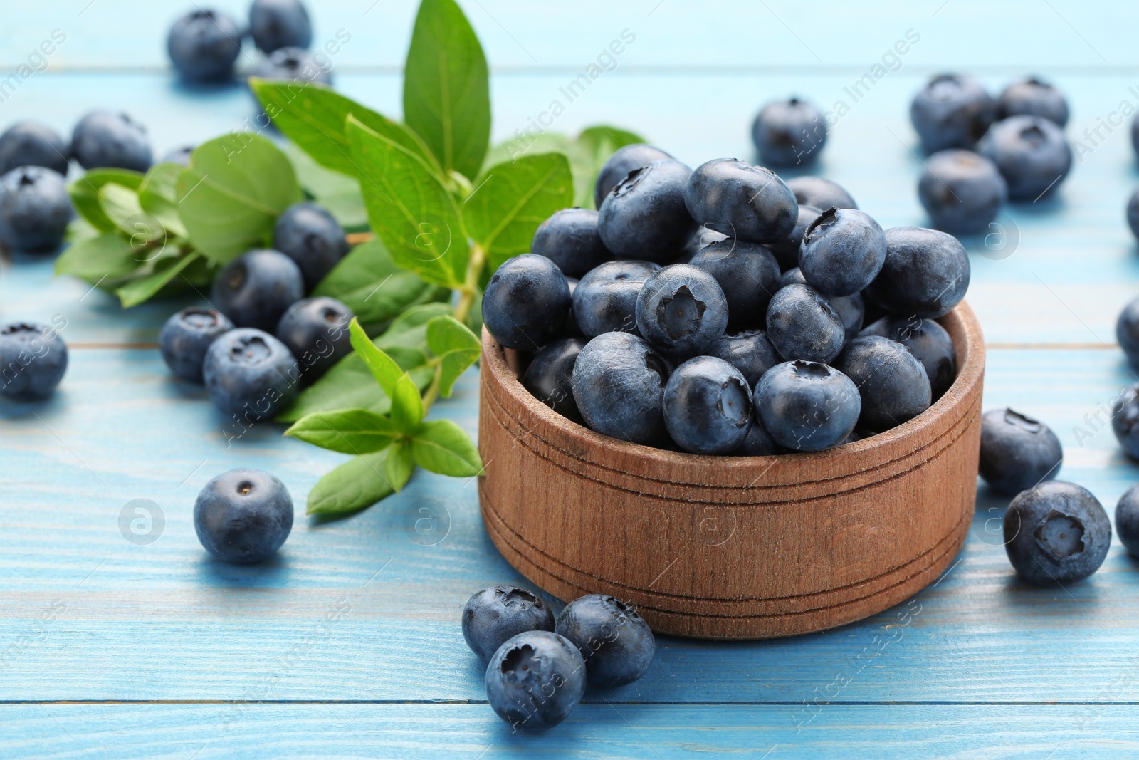 Photo of Tasty fresh blueberries on light blue table, closeup