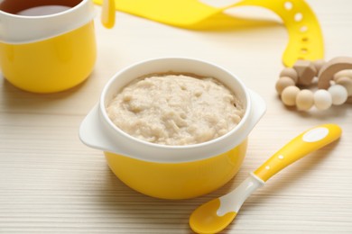 Plastic dishware with healthy baby food on white wooden table, closeup