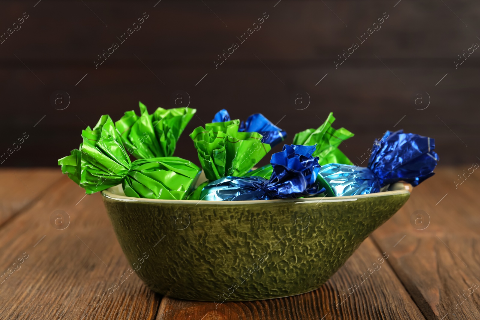 Photo of Candies in colorful wrappers on wooden table