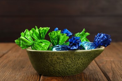 Photo of Candies in colorful wrappers on wooden table